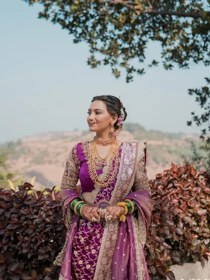 The bride looking radiant against a natural backdrop. Her purple Nauvari, combined with soft, glowing makeup, creates a breathtaking sight.