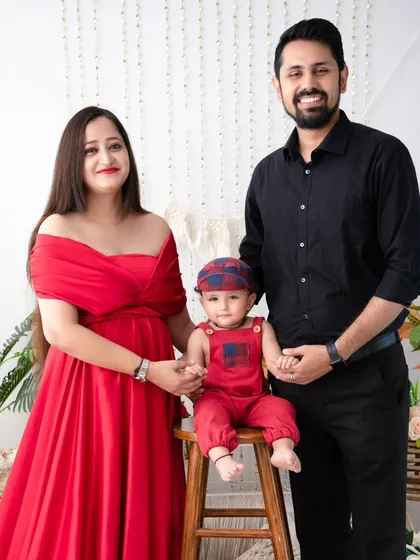 A classic family portrait with a pop of color. The mother's red dress and baby's red overalls add a vibrant touch to this session.
