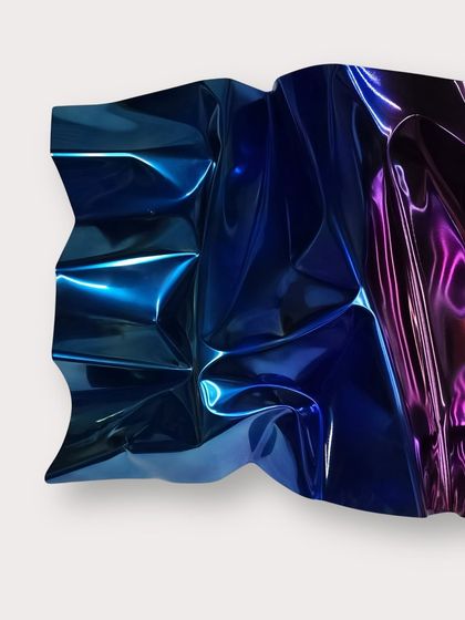 The sharp folds in M133 create dramatic shifts in color, from deep blue to electric violet, as light hits the surface.