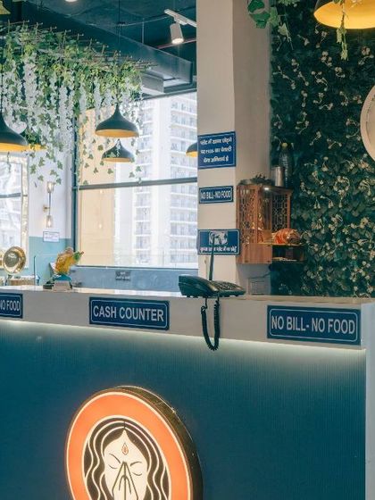 The cash counter and entrance area of our Spectrum Mall restaurant, featuring our logo and a green wall accent.