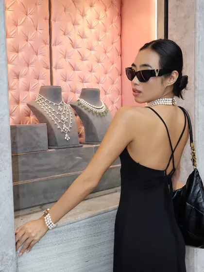 Inspired by Audrey, created for you. A model window-shopping our pearl collection, wearing a chic pearl choker and matching bracelet.