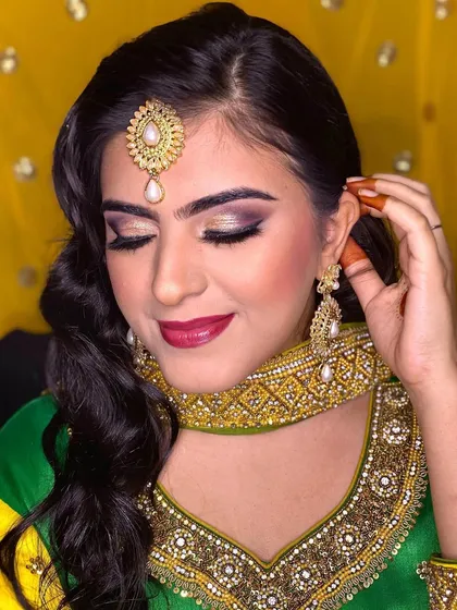 A full view of this Roka makeup, showing how the bold eye makeup is balanced with a radiant complexion and a deep berry lip. The entire look is coordinated with her vibrant green and yellow outfit.