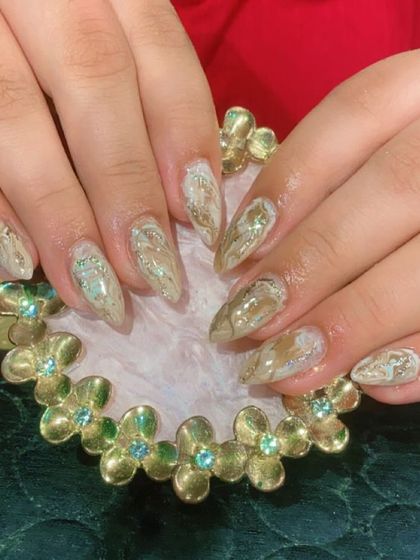 An elegant and earthy marble design using neutral tones with hints of green and gold on stiletto nails.