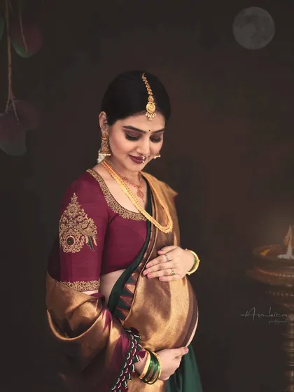 A gentle and loving portrait where the mother-to-be cradles her bump. The focus is on her serene expression and the intricate details of her attire, creating a timeless piece of ethnic maternity art.