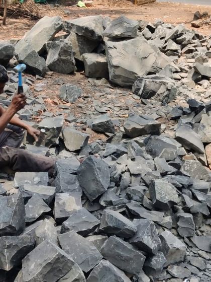 A close-up of a worker using a hammer and chisel to dress raw stone. This traditional technique requires immense skill and patience, resulting in unique textures that cannot be replicated by machines.