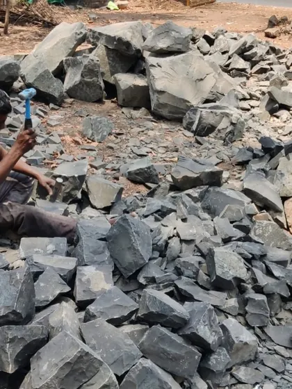 A close-up of a worker using a hammer and chisel to dress raw stone. This traditional technique requires immense skill and patience, resulting in unique textures that cannot be replicated by machines.