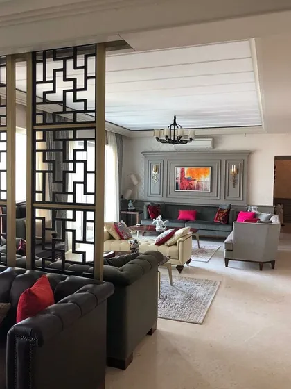 A wider view of the living area, showing how the geometric room divider separates the formal seating area from the rest of the space. This approach allows for an open feel while creating functional, intimate zones.
