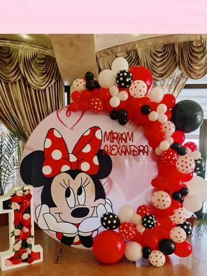 A classic Minnie Mouse theme on a circular backdrop, with red, white, and black polka-dot balloons.