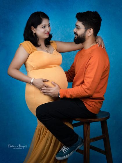 A vibrant and loving portrait. The contrast between her yellow dress and his orange sweater against the blue background is stunning.
