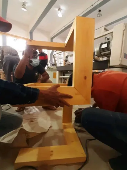 Students work together to assemble the frame of a modern coffee table, ensuring all mitered corners are perfectly aligned.