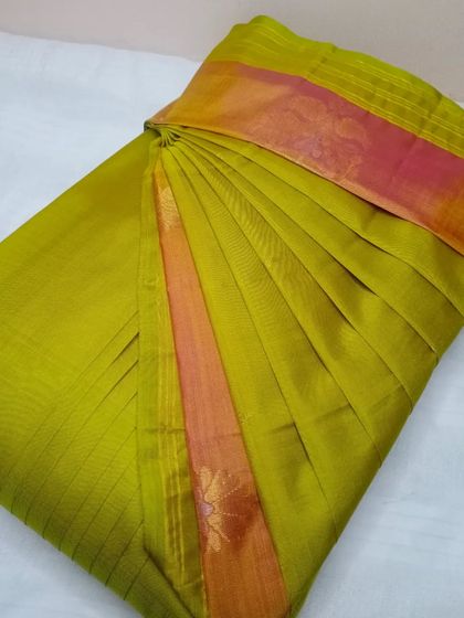 An olive green saree with a pink and orange border. The pleats are done neatly, making it ready for a quick and elegant drape.
