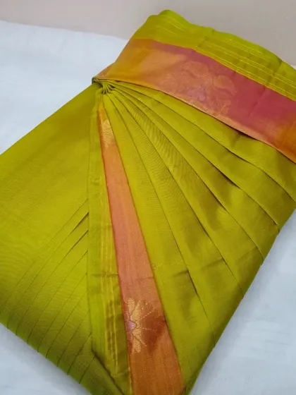 An olive green and pink silk saree, pleated like a pro.