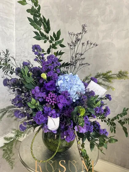 In an introspective January mood. This arrangement captures epic passion on a small scale, with a single blue hydrangea creating a striking contrast against a sea of deep purple flowers.