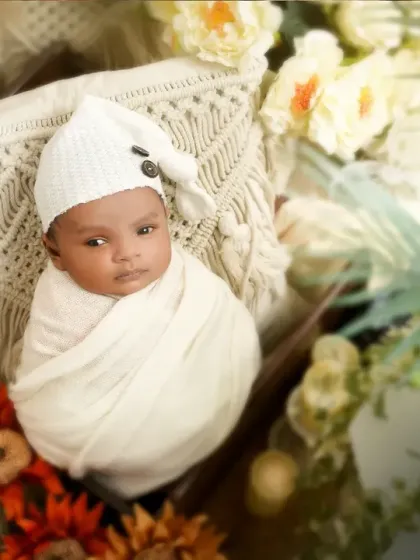 An awake and curious newborn in a white swaddle and sleepy hat. We are always ready to capture those beautiful open-eyed moments too.