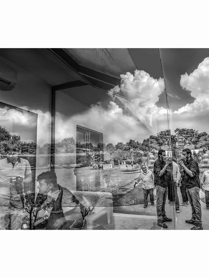 A black and white image where the dramatic clouds of the sky are reflected onto the glass walls of an art gallery. This photograph plays with architecture and nature, merging the outside world with the interior space.