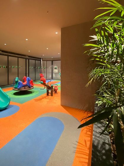 The flowing, colorful graphics on the rubber flooring create a sense of energy and openness, turning a simple concrete space into a vibrant play-scape.