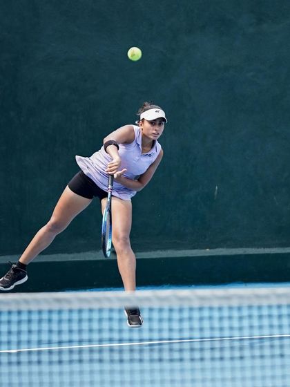 A player caught at the peak of her service motion, demonstrating the power and athleticism developed through our strength and conditioning programs.