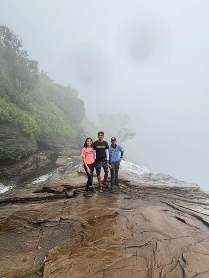 Three friends stand at the edge of Bandaje Falls, surrounded by thick fog.