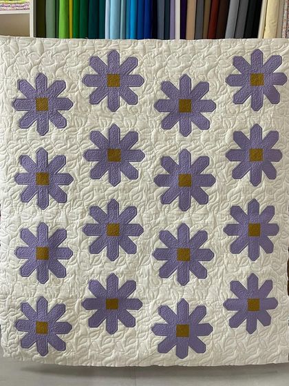 A lovely daisy quilt where the background is filled with a leaf-and-vine free-motion quilting pattern.