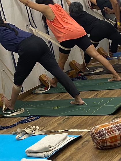 A close-up of the leg and foot alignment in Parsvottanasana at the wall. Notice the use of belts and blocks to ensure stability and correct form.