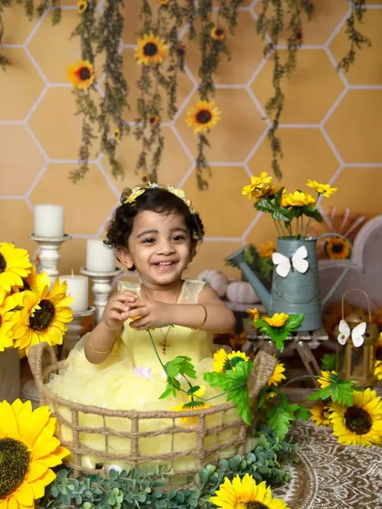 A genuinely happy moment captured as the toddler plays with a sunflower during her themed photoshoot.