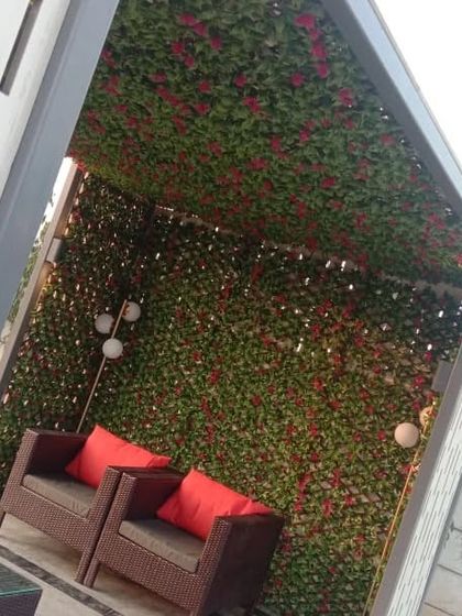 Another seating nook created with a trellis covered in artificial bougainvillea. The red flowers add a vibrant pop of color to the cozy space.