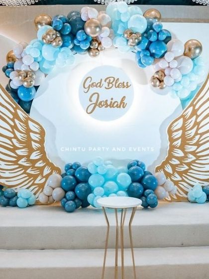An elegant Holy Communion balloon decoration with large angel wings. The blue, white, and gold balloons create a stunning backdrop for the stage.