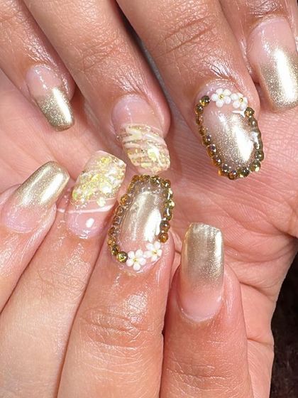 Go for gold with this luxurious set. It combines gold chrome nails, glitter accents, and a statement nail with a border of gold beads and tiny 3D flowers for a truly glamorous look.