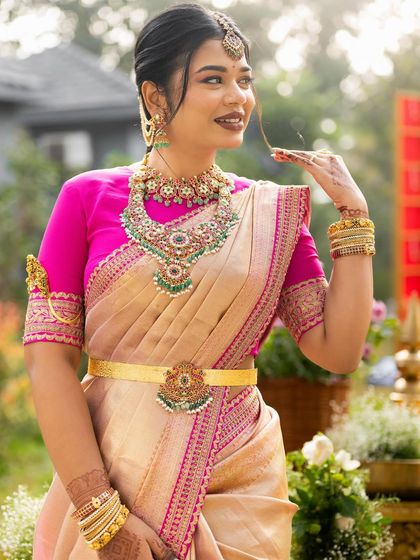 A close-up of the bride, showcasing her beautiful makeup and the intricate details of her pink embroidered blouse.