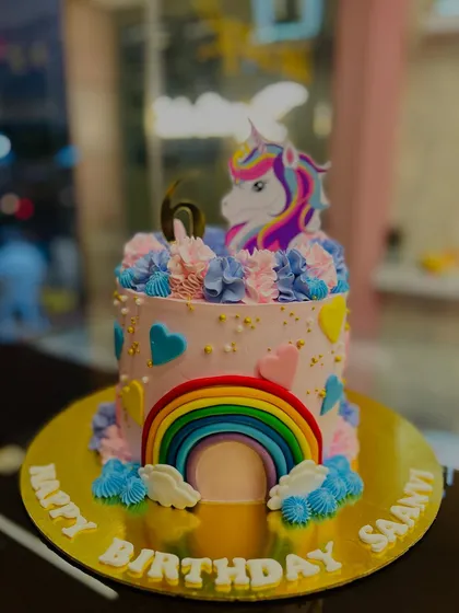 A magical unicorn and rainbow cake for a 6th birthday. The colorful rainbow arching over the cake and the pretty unicorn topper make it a bright and cheerful centerpiece.