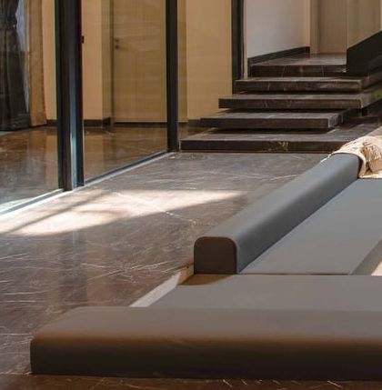 A detail of the sunken lounge area, showing the custom low-profile seating and the seamless transition between different types of marble flooring.