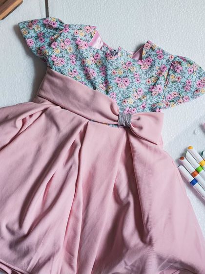 A beautiful flat-lay of a dusty pink dress with a floral bodice, surrounded by colorful markers. It’s a nod to the creativity and artistry that goes into each design.