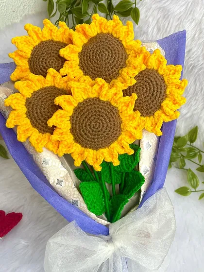 The beautiful five-sunflower bouquet, held in hand. The purple wrapping makes the yellow of the sunflowers stand out even more.