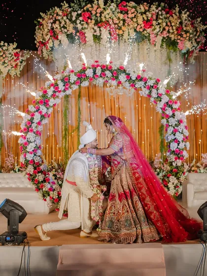 A varmala ceremony set against a circular floral arch, with perfectly timed cold pyros creating a halo of sparks. The design focuses on creating a perfect frame for the couple.