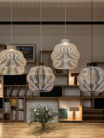 Four Kuulto pendants in various finishes (natural birch, white, and black) are displayed together, demonstrating the versatility of the design. This shows how different finishes can be used to match a range of interior color palettes.