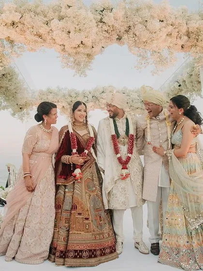 A beautiful family portrait of Rahul and Pallavi with their parents on the wedding stage in Thailand. This image captures the union of two families with the stunning ocean view behind them.