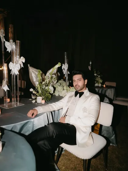 The groom looking dapper at a table adorned with modern centerpieces and candlelights during the reception.