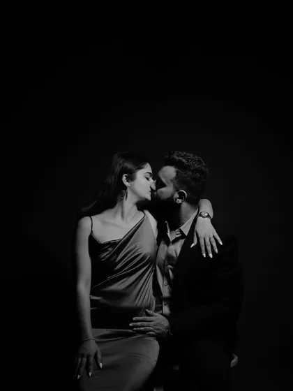 A beautifully composed black and white shot capturing a tender kiss. The negative space and classic posing make this a timeless piece of art.