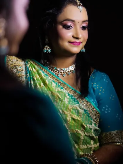 A beautiful portrait of a woman in a green and blue saree, likely a guest or family member at a wedding event.