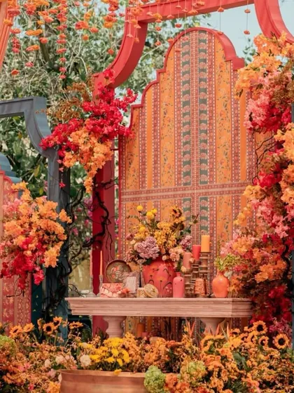 A beautiful haldi seating area with a terracotta and orange color palette. The decor features traditional Indian patterns, intricate backdrops, and an abundance of marigolds and other flowers.
