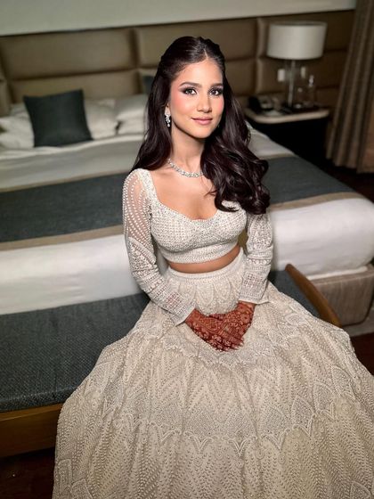 The full look in her stunning white lehenga. The subtle makeup is perfect for her engagement, creating a look that is both elegant and understated.