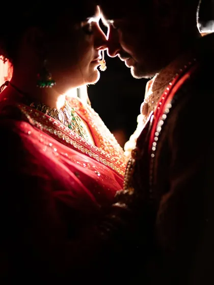 An artistic silhouette of Priya and Kishan sharing an intimate moment. The dramatic backlighting creates a beautiful rim light, highlighting their connection while shrouding them in romantic shadow. This is a perfect example of creative couple portraiture.