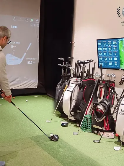 The complete setup: a golfer in the bay, the TrackMan screen displaying real-time data, and a variety of demo clubs ready to be tested.