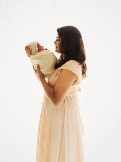 A similar pose from the side, showing the mother's joyful smile as she holds her new baby. The light and airy feel is simply beautiful.