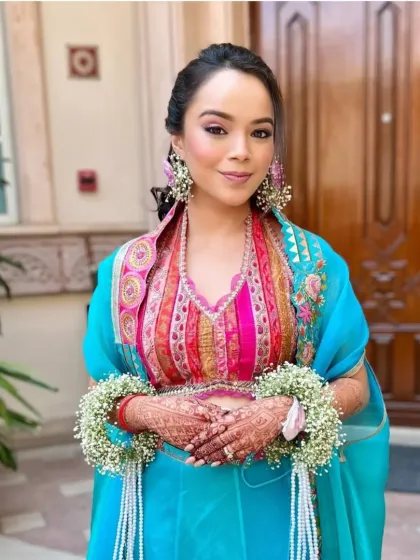 A closer view of the Mehendi bride's textured ponytail and floral accessories. The style is designed to complement her colorful outfit and fresh flower jewelry.
