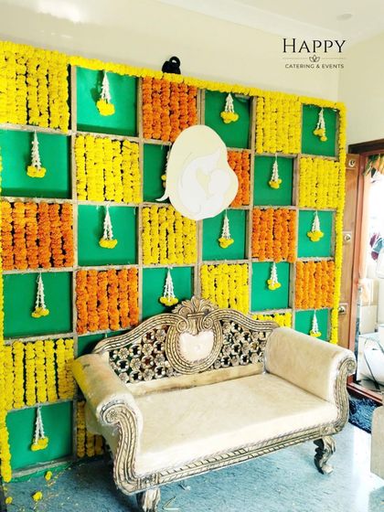 A traditional marigold backdrop in yellow and orange. The design includes hanging jasmine strings and a cutout of a mother and child, perfect for a Godh Bharai ceremony.
