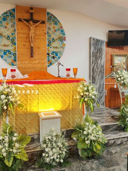 We also provide floral decorations for the church ceremony itself. This Holy Communion setup includes multiple arrangements of white flowers and green foliage placed around the altar.