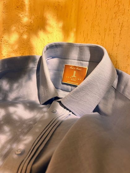 This light blue linen shirt features subtle pintuck details, adding a touch of custom craftsmanship. It's the perfect shirt for staying cool and stylish during the summer.