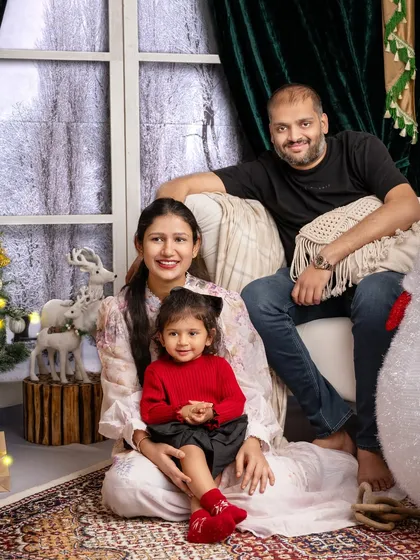 A sweet family portrait, with the parents looking lovingly at their little one, all gathered for a Christmas photo.