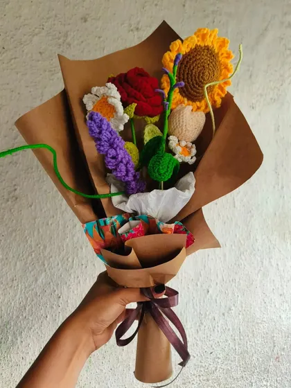 Holding up one of my signature mixed floral bouquets. Each one is a unique piece of art, combining different yarn flowers into a beautiful arrangement.